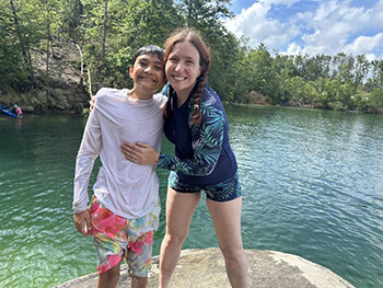 A duo standing side by side in front of a lake.