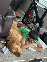 A child and dog laying side by side.