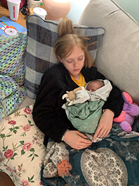 A child and baby sleeping on a couch.