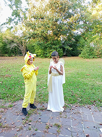 Two children standing outside wearing costumes.