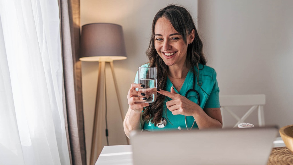 A medical professional holding up a glass of water.