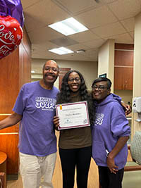Three people standing side by side smiling at the camera.