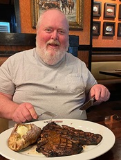 A man eating a steak in a restaurant.