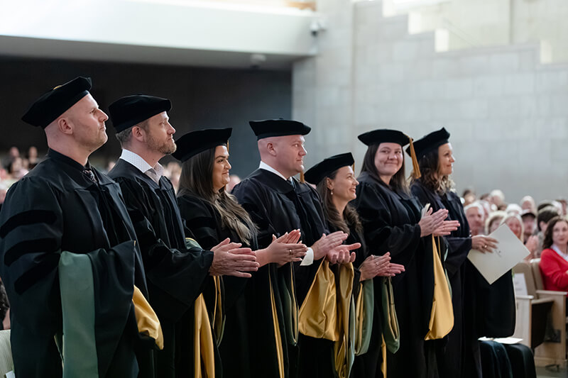 Graduates clapping at a graduation ceremony.