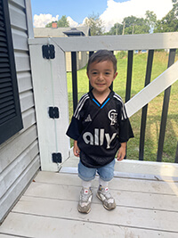 A child standing outside smiling at the camera.