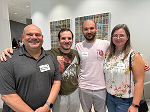Four people standing side-by-side smiling at the camera.