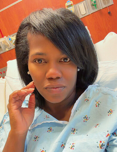 A woman with black hair resting in a hospital bed.
