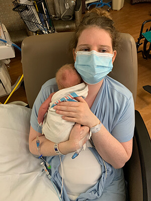 A person wearing a mask and holding a baby.