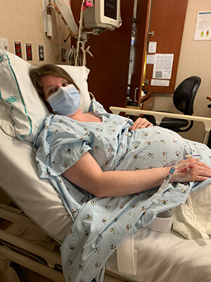 A person wearing a mask in a hospital bed.