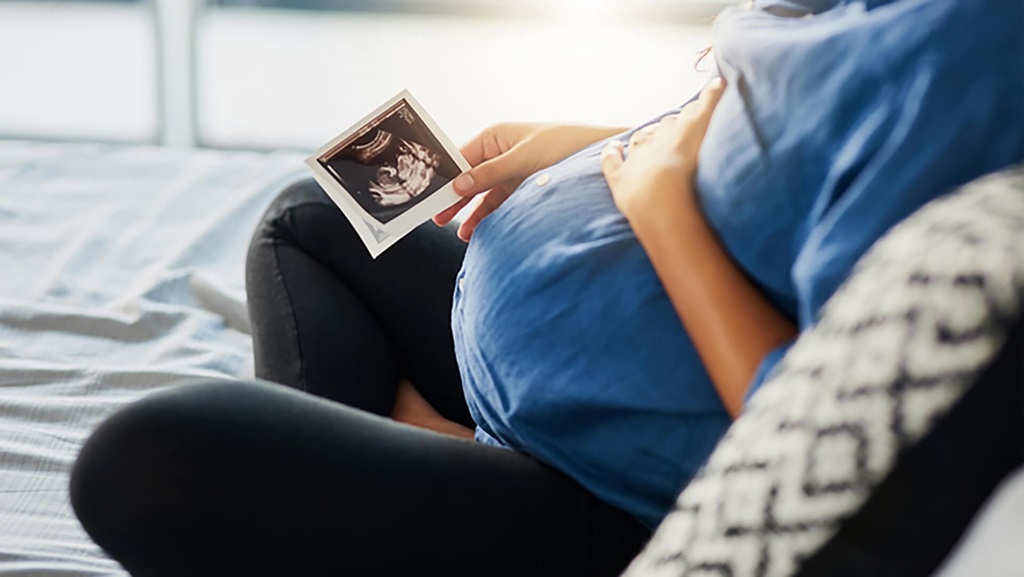 A pregnant person looking at an ultrasound.