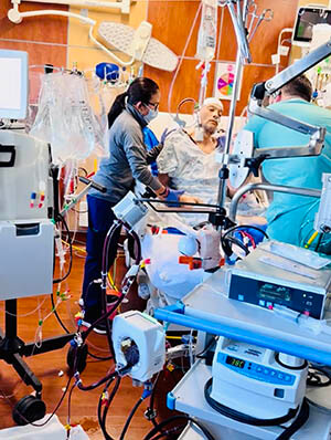 A man in a medical bed surrounded by medical equipment.