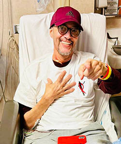 A man sitting in a medical bed smiling at the camera.