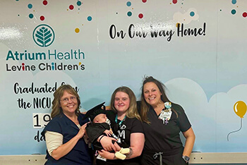 A group of people holding a baby.