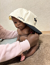 A baby wearing an oversized hat.