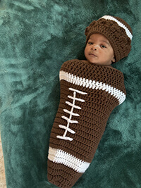 A baby dressed in a football outfit.