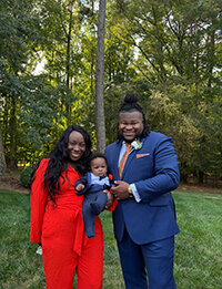 A family standing outside smiling at the camera.