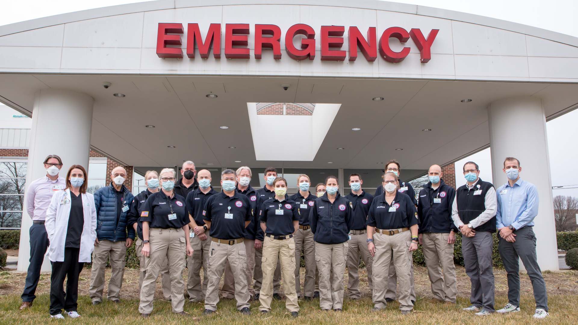 16 medical professionals from The U.S. Department of Health and Human Services National Disaster Medical System (NDMS) standing in front of Atrium Health Pineville