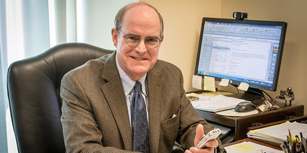 Lawyer and cancer survivor Eddie Poe sits at his law firm desk.