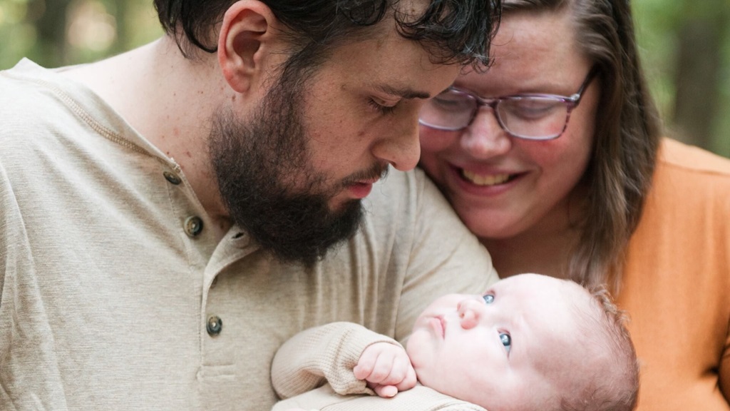 Andy, his wife, and their baby huddled together for new family photo shoot.