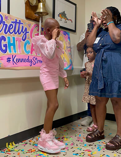 A young girl in pink and a woman in a blue dress crying together.