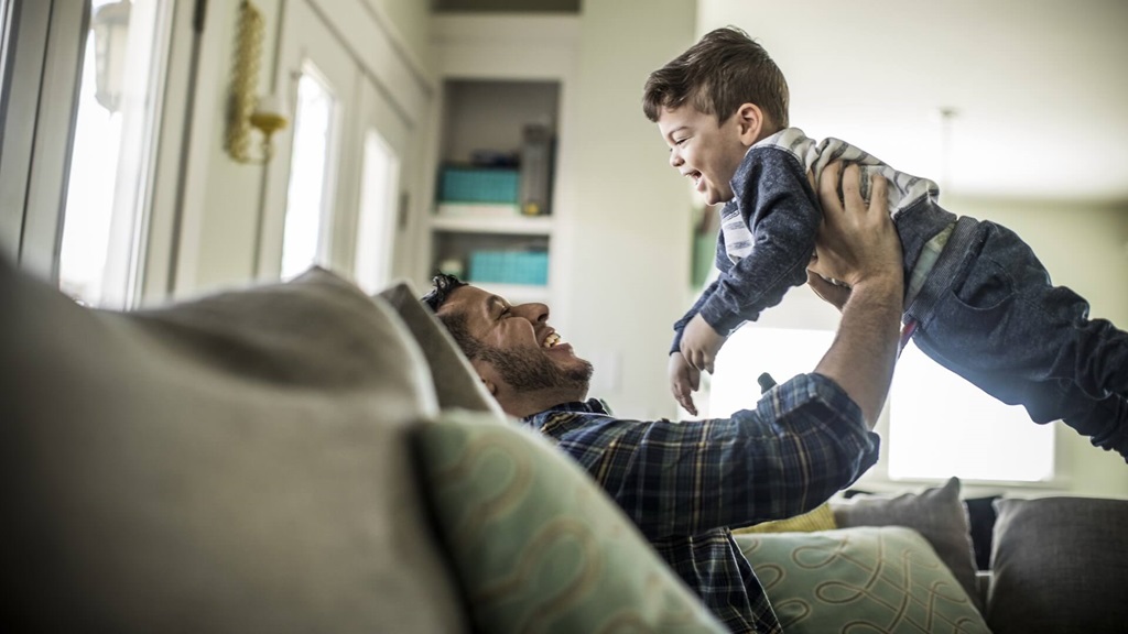 Adult male holding male child above him