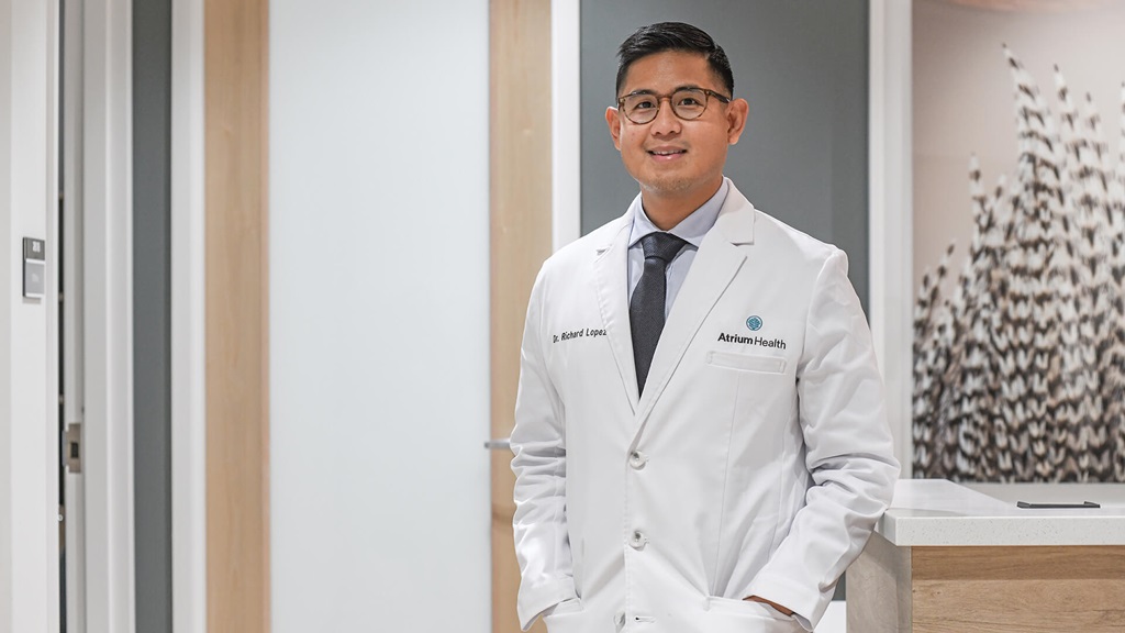 A medical professional wearing a lab coat smiling at the camera.