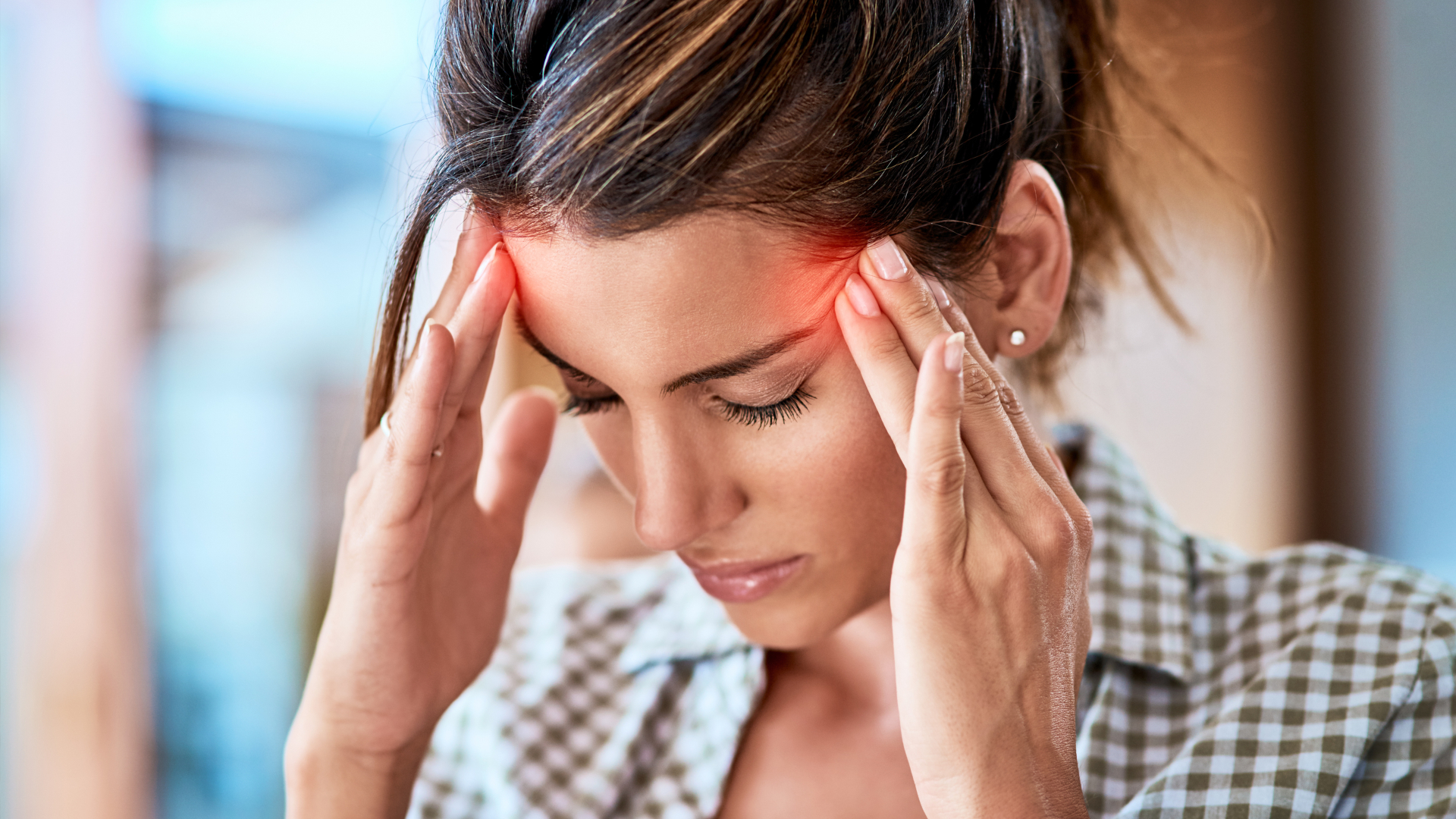 Woman experiencing migraine holding her head in agony