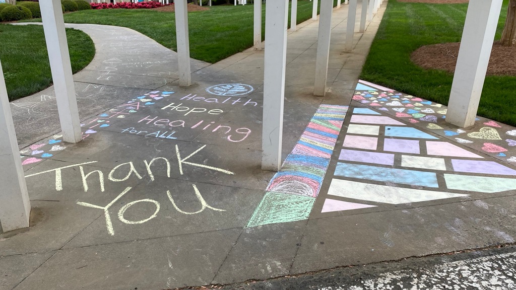 Patients and teammates draw inspiring messages in front of facilities for Atrium Health care teams. 