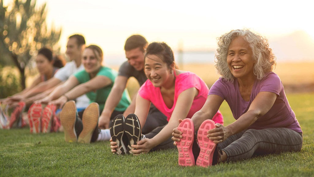 Group of adults stretching in open field.