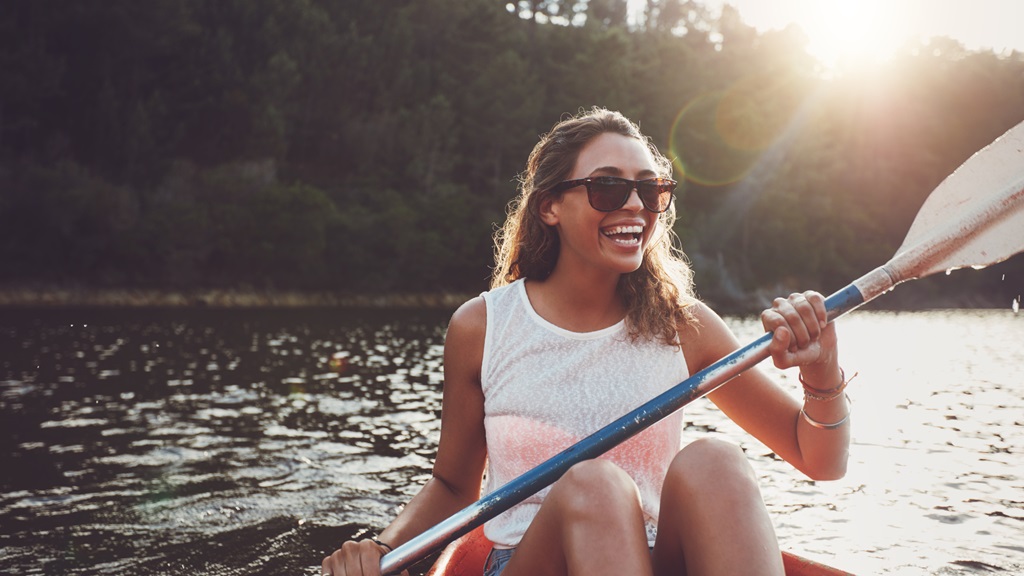 Woman kayaking on lake during warm summer day.