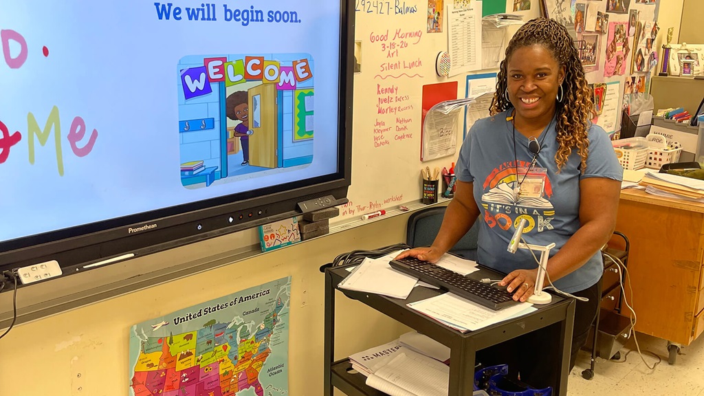 Shermeine Hammie standing with a cart in the front of a classroom.