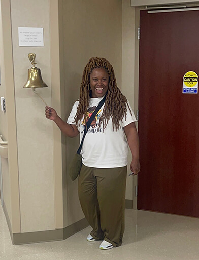 Shermeine Hammie ringing a bell on a wall.