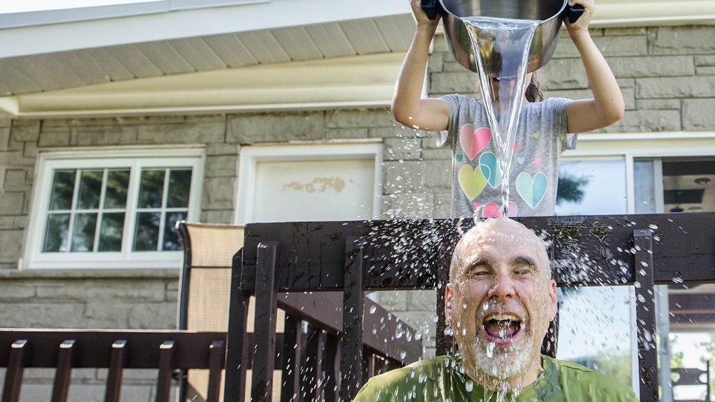 A young girl pouring water on a man's head.