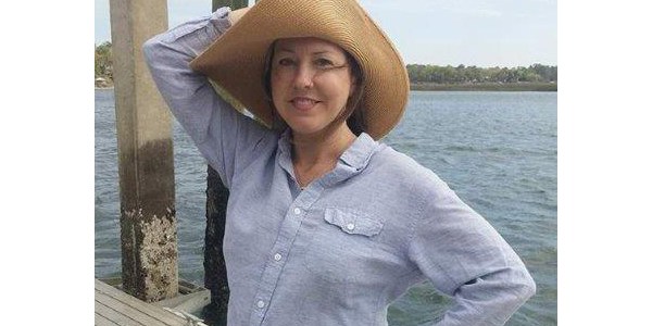 Woman Standing Outdoors Wearing a Floppy Hat To Protect Against the Sun