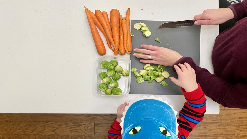 Adult cutting up vegetables for a kid