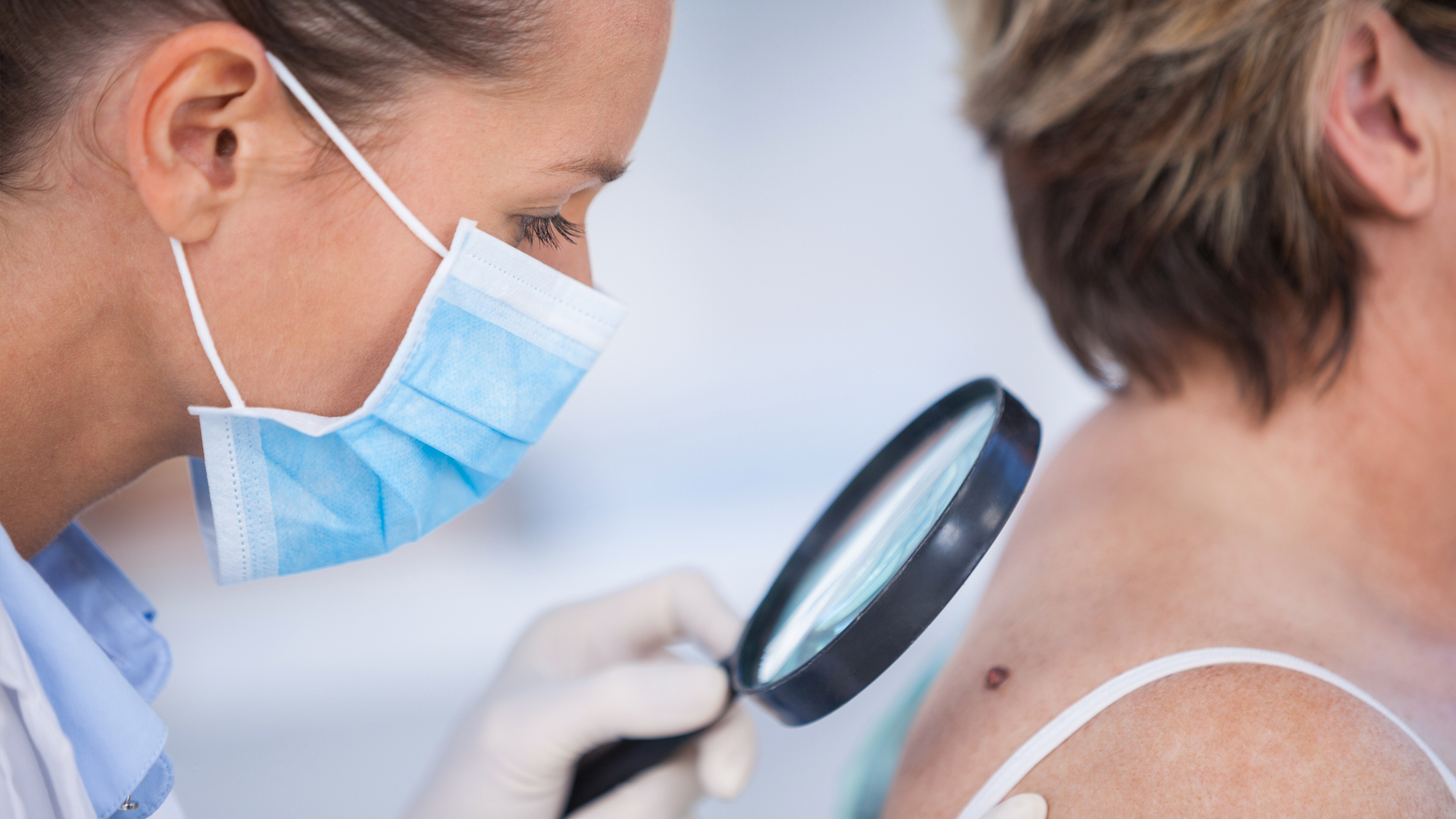 Doctor evaluates patient's mole for signs of melanoma