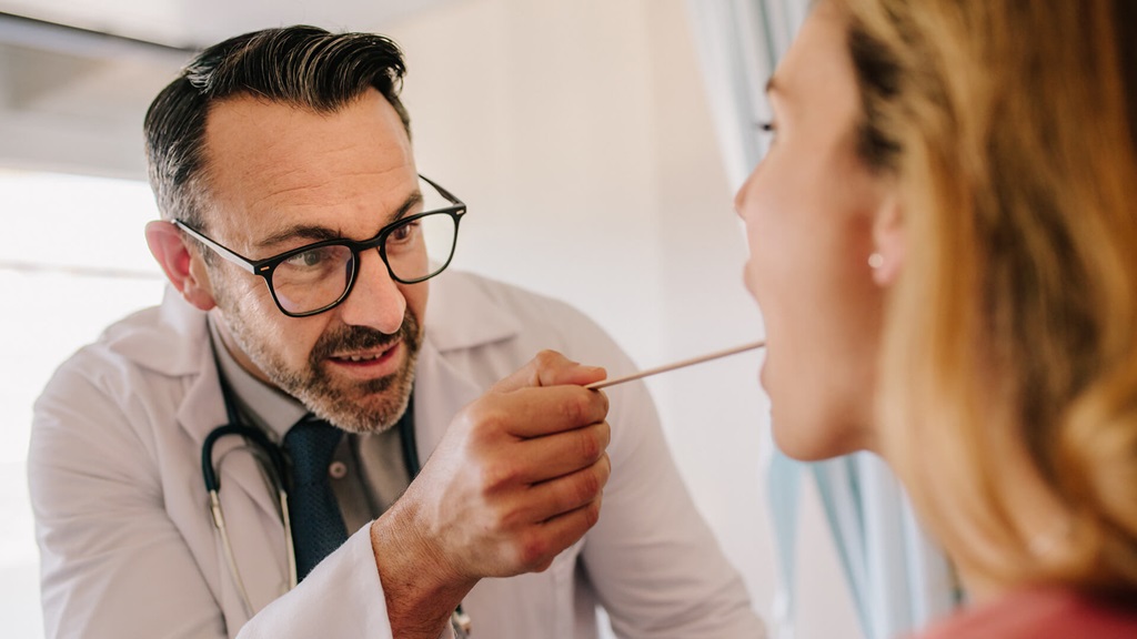 Doctor using a tongue depressor on a patient 