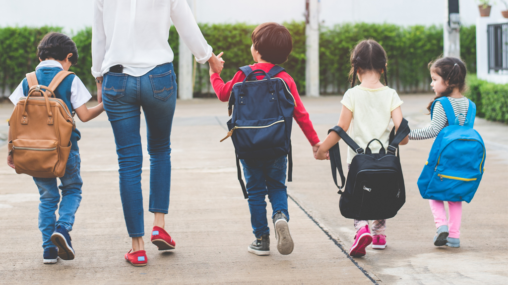 children with backpacks walking with parent 