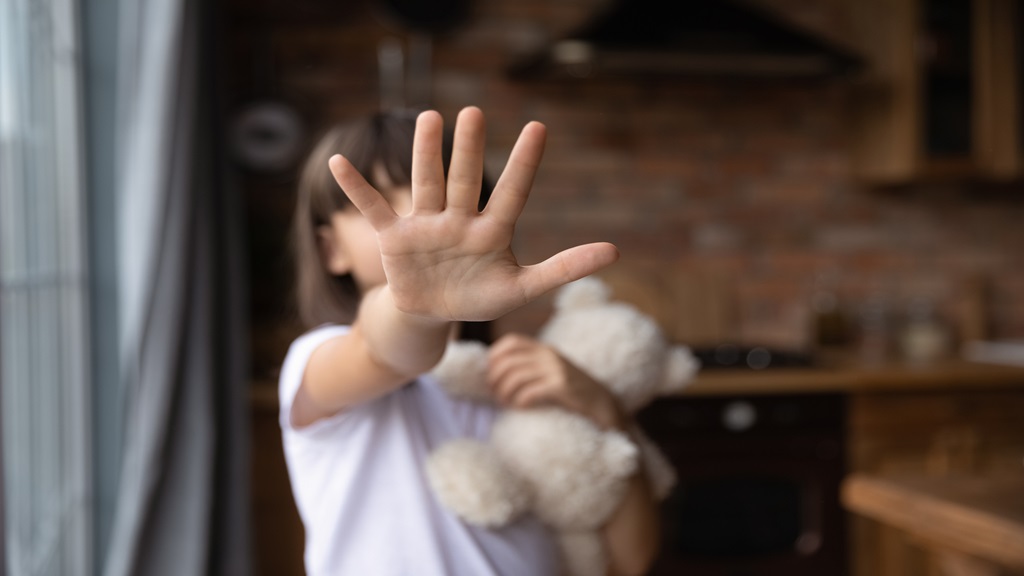 Child with hand out covering face 