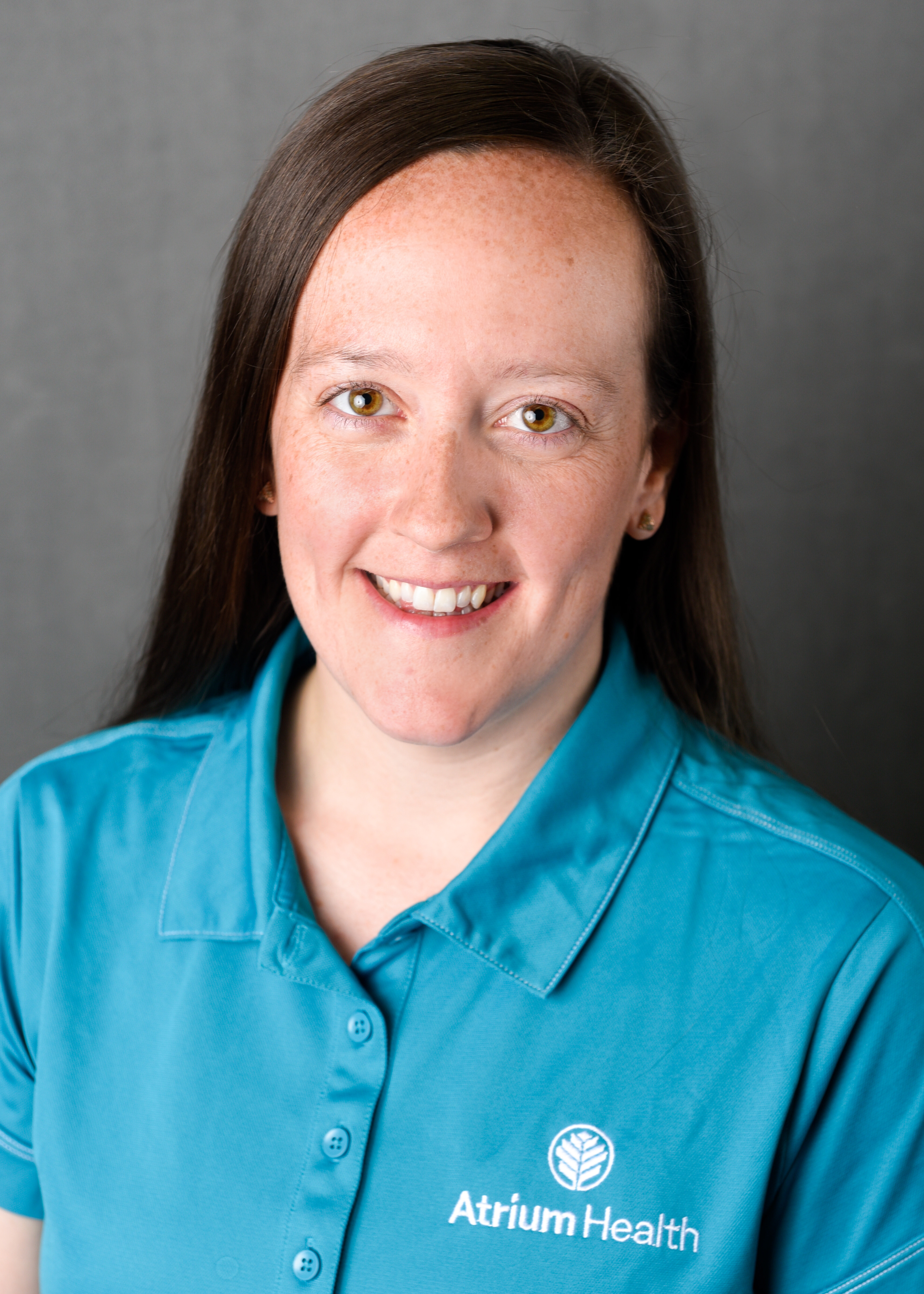 Headshot of a woman smiling at the camera wearing a teal Atrium Health shirt