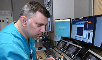 A man wearing scrubs looking at medical equipment.