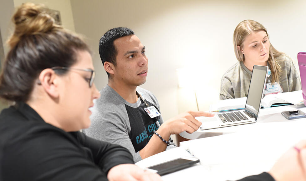 A group of students taking notes on laptops.