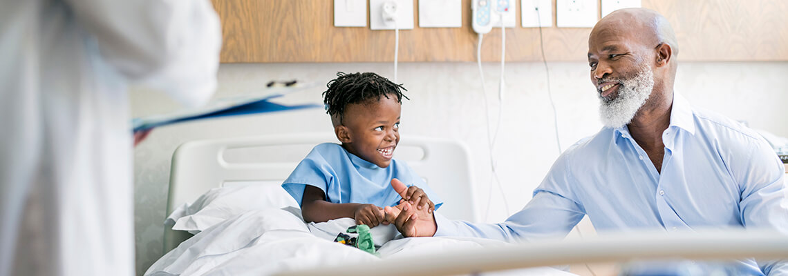 Grandfather Playing With Ill Grandson In Hospital